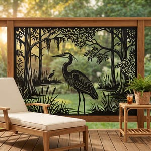 Puede incluir: Una pantalla de privacidad decorativa de metal negro con una silueta detallada cortada con láser de una garza grande de pie en un paisaje pantanoso con árboles, musgo colgante y espadañas. El diseño representa una escena de humedal natural.