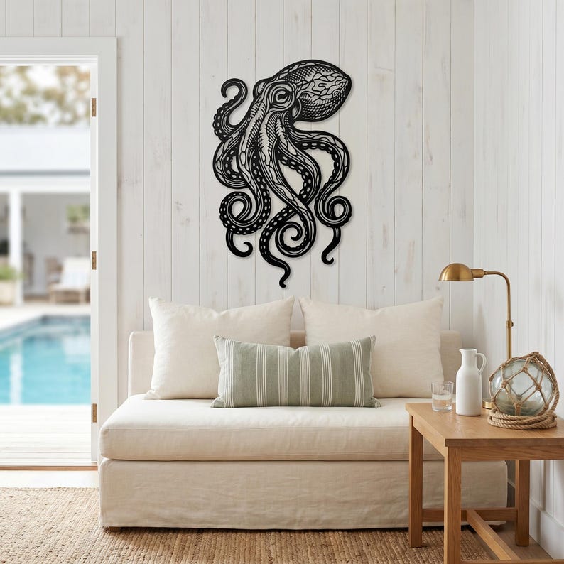 May include: Black metal octopus wall art with intricate details. The octopus is mounted on a white wooden wall. The tentacles curl and swirl, creating a dynamic and eye-catching design. This nautical-themed decor adds a touch of the ocean to any space.