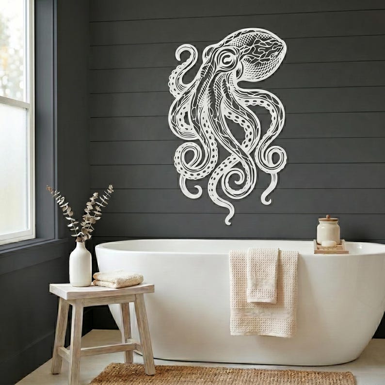 May include: White metal octopus wall art with intricate details, mounted on a dark gray wall. The octopus design features detailed lines and swirling tentacles, creating a striking visual element for home decor.