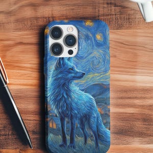 Puede incluir: Funda de teléfono azul con una ilustración de zorro estilizada inspirada en "La noche estrellada" de Van Gogh. El diseño incluye un zorro azul, un cielo arremolinado y un pueblo. La funda está hecha de un material duradero.