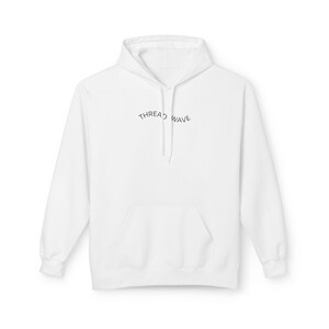 May include: A white hoodie with a front pocket and drawstring. The text "THREAD WAVE" is arched across the chest in black. The hoodie is made of a soft material and is suitable for casual wear.