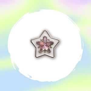 May include: A star-shaped pin with a white enamel base and a silver-coloured border. The centre features a pink, flower-like design. The pin is set against a soft, colourful background.