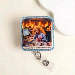 May include: Square badge reel with a glittery blue border. The image depicts a doll at a desk with a burning office in the background. The doll is holding a pink mug that says "I CAN'T". The text "everything is under control (no)" is at the bottom.