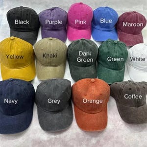 May include: A collection of baseball caps in various colors, including black, purple, pink, blue, maroon, yellow, khaki, dark green, green, white, navy, grey, orange, and coffee. Each cap has a curved brim and a top button. The color of each cap is labeled.