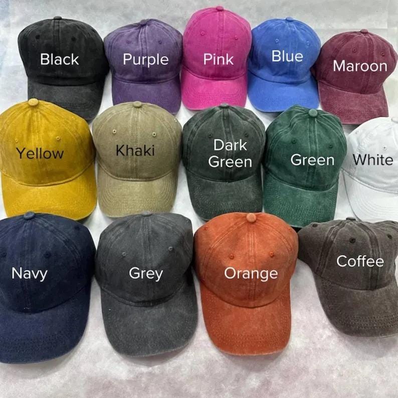 May include: A collection of baseball caps in various colors, including black, purple, pink, blue, maroon, yellow, khaki, dark green, green, white, navy, grey, orange, and coffee. Each cap has a curved brim and a top button. The color of each cap is labeled.