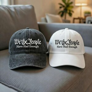 May include: Two baseball caps, one charcoal gray and one white, are displayed. Both caps feature the text "We the People Have Had Enough" in a decorative font. The caps are sitting on a gray surface.