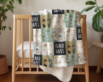 Puede incluir: Una manta para bebé blanca y azul con un diseño de patchwork que presenta tablas de surf, palmeras y el nombre "Oliver Hayes" repetido en toda la superficie.