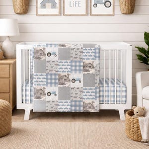 May include: A patchwork baby quilt featuring a farm-themed pattern with blue and gray colors. The quilt displays repeating illustrations of barns, tractors, farm animals, and plaid fabric squares, draped over a white wooden crib with a matching sheet.