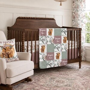 May include: A patchwork baby blanket featuring a repeating pattern of Highland cows, floral arrangements, and polka dots in muted tones of sage green, dusty rose, and cream. The blanket includes the name Brynn Ava printed on several squares.