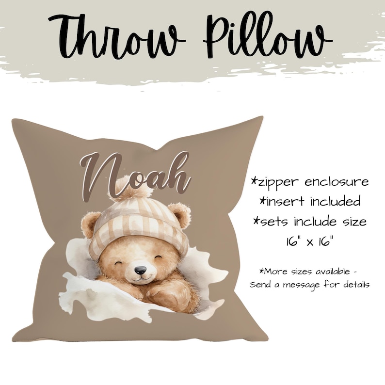 May include: A taupe throw pillow with a watercolour illustration of a teddy bear wearing a striped hat. The pillow is personalised with the name "Noah". The pillow measures 40.6 cm x 40.6 cm.
