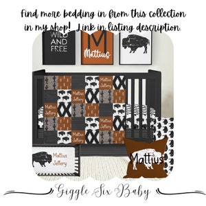 May include: A black and white crib with a brown, black, and white patterned quilt. The quilt features a buffalo silhouette and cactus designs. The crib also has a brown pillow with the name "Mattius" on it. The crib is decorated with a black and white buffalo print and a sign that says "Wild and Free".