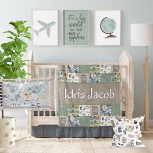 May include: A baby crib with a green and gray travel themed bedding set. The bedding features a patchwork design with images of airplanes, hot air balloons, and maps. The crib also has a personalized pillow with the name "Idris Jacob" embroidered on it.