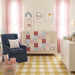 May include: A nursery room featuring a white cot with a patchwork quilt displaying rainbows, suns, and the text You Are My Sunshine. A navy blue armchair with a matching pillow, a yellow and white checkered rug, and wall art with rainbows.