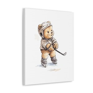 May include: A brown teddy bear wearing a white hockey helmet and jersey, holding a hockey stick. The bear is standing on a white background.
