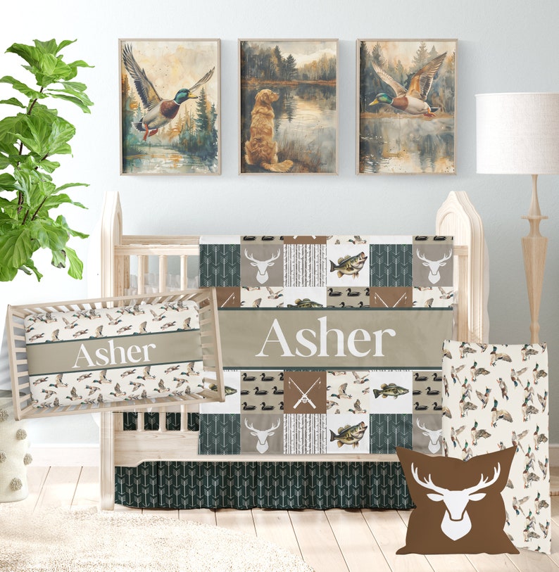 May include: A baby crib bedding set with a woodland theme. The set includes a quilt, a fitted sheet, a crib skirt, a pillow, and a pillowcase. The quilt features a patchwork design with images of deer, fish, and ducks. The fitted sheet and pillowcase have a pattern of ducks. The crib skirt has a pattern of arrows. The pillow has a brown deer head design. The set is personalized with the name "Asher".