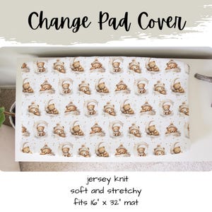 May include: A white change pad cover featuring a pattern of sleeping teddy bears on crescent moons. The text "Change Pad Cover" is at the top. The cover is jersey knit and fits a 40.6cm x 81.3cm mat.