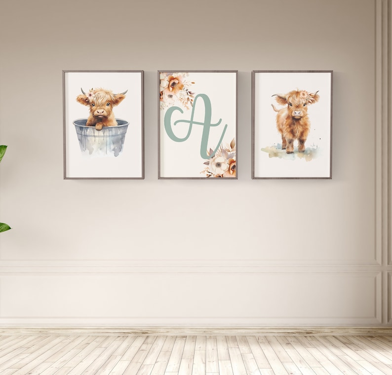 Puede incluir: Tres impresiones enmarcadas con ilustraciones de acuarela de una vaca de las tierras altas. La primera impresi&oacute;n muestra una vaca sentada en un cubo, la segunda impresi&oacute;n muestra la letra "A" con acentos florales, y la tercera impresi&oacute;n muestra una vaca de pie sobre un fondo de acuarela.