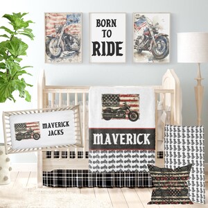 May include: A baby crib bedding set with a black and white plaid crib skirt, a white blanket with a red, white, and blue American flag and a motorcycle design, a white pillow with a red, white, and blue American flag and a motorcycle design, and the text "Maverick Jacks", and a white pillow with a black and white motorcycle pattern.