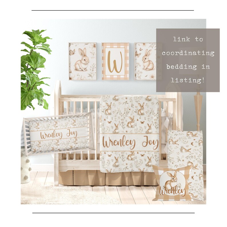 May include: A white crib with a brown and white floral patterned blanket and pillow. The pillow has the name "Wrenley Joy" embroidered on it. There are three framed prints above the crib, each featuring a bunny rabbit and floral designs. The prints have a white background and gold accents. The text "link to coordinating bedding in listing!" is in the upper right corner of the image.
