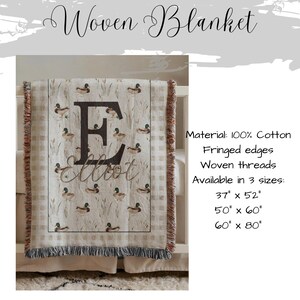 May include: A woven blanket featuring a repeating mallard duck and reed pattern with a large letter E and the name Elliot printed in the center. The blanket has fringed edges and is made of 100% cotton. Available in 37 by 52, 50 by 60, and 60 by 80 inches.