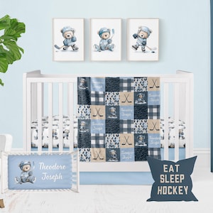 May include: A baby crib set with a hockey theme. The set includes a crib, bedding, and framed artwork. The bedding features a patchwork design with hockey sticks, teddy bears, and the name "Theodore Joseph". The artwork depicts teddy bears playing hockey. A pillow says "EAT SLEEP HOCKEY".