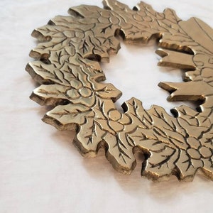 Pode incluir: Uma detalhada coroa de metal dourado com um design de folhas e bagas. A coroa &eacute; circular, com uma sec&ccedil;&atilde;o em falta, e assenta numa superf&iacute;cie branca. O design &eacute; intrincado e parece ser de metal fundido.
