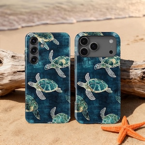 Könnte beinhalten: Zwei Smartphone-Hüllen mit einem türkisfarbenen Schildkrötenmuster auf dunkelblauem Hintergrund. Die Hüllen liegen auf einem Sandstrand, mit einem Seestern und Treibholz im Hintergrund. Die Schildkröten haben weiße Umrisse.