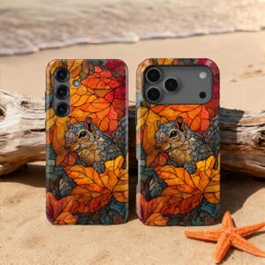 Puede incluir: Dos fundas para teléfono con diseño de ardilla. Las fundas presentan una ardilla rodeada de hojas de otoño naranjas y rojas. Las fundas están en una playa de arena con una estrella de mar y madera flotante.