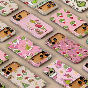 May include: A collection of phone cases featuring various designs with the Grinch character and Christmas-themed elements. The cases showcase a range of colors, including pink, green, and beige, with festive patterns and illustrations.