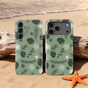 May include: Two phone cases with a green background and a repeating pattern of pine cones, pine needles, and snowflakes. The phone cases are on a sandy surface with a starfish and driftwood.