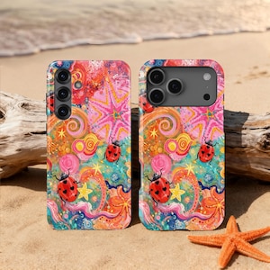 May include: Two phone cases featuring a vibrant, colorful pattern of red ladybugs with black heart-shaped spots, yellow starfish, and swirling abstract shapes in shades of pink, orange, blue, and yellow against a multi-colored background.