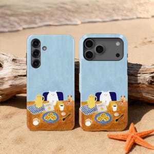 以下が含まれることがあります： クッキー、ティーポット、カップのあるテーブルにいる猫の気まぐれなイラストが描かれた2つの携帯電話ケース。背景は水色です。ケースは、ヒトデと流木のある砂浜にあります。