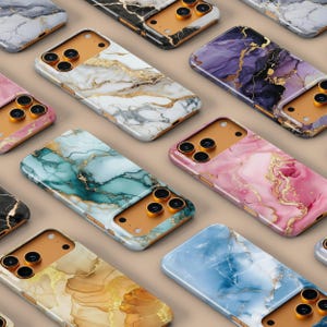 May include: A selection of smartphone cases with marble patterns in diverse colours, such as white, pink, blue, and teal. The cases have gold detailing and are displayed on a neutral background. The camera cutouts are visible.