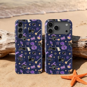 May include: Two phone cases with a dark blue background and a repeating pattern of black cats wearing witch hats, brooms, stars, moons, potion bottles, and spell books in purple and gold. The cases are on a sandy beach with a starfish and driftwood.