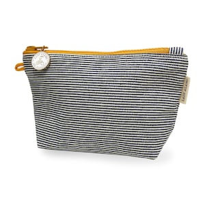 Puede incluir: Una peque&ntilde;a bolsa de cremallera a rayas con una cremallera amarilla y un charm de metal con el texto "Lady Alamo San Francisco" y un gr&aacute;fico de bicicleta.