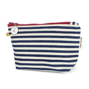 Puede incluir: Una bolsa de maquillaje de lona a rayas azules y blancas con una cremallera roja y un dije plateado con un dise&ntilde;o de bicicleta. La bolsa tiene el texto "LADY ALAMO" impreso en el lateral.