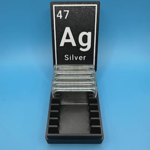May include: A black and clear silver display stand with the periodic table symbol for silver, Ag. The stand has a black base with slots, a clear glass shelf, and a black sign with the number 47, the symbol Ag, and the word "Silver".