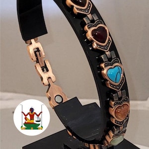 May include: A link bracelet featuring a black band with copper-toned metal accents and heart-shaped inlays in various colours including turquoise, dark red, and light green. The bracelet includes a metallic clasp mechanism and a small circular logo.