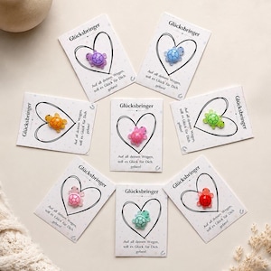 May include: Seven small, colorful turtle figurines attached to individual white cards. Each card features a black heart outline, the text "Glücksbringer" at the top, and the German phrase "Auf all deinen Wegen, soll es Glück für Dich geben!" printed below.