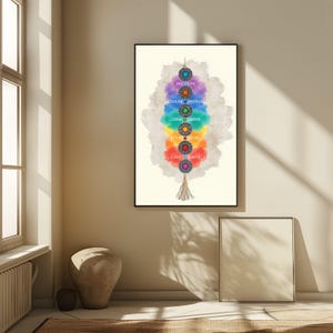 May include: A framed art print featuring a colorful chakra design. The artwork displays seven circular elements in a vertical arrangement, each with a different color and associated word. A decorative tassel hangs at the bottom.