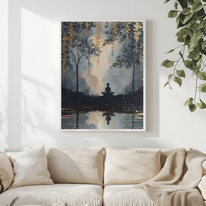May include: A framed art print depicts a serene scene of a person meditating by a reflective body of water. The artwork features a color palette of blues, golds, and whites, with trees and foliage. The person's silhouette is mirrored in the water.