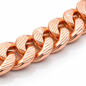 Pode incluir: Close-up de um colar de corrente em ouro rosa. As elos são grossos, arredondados e apresentam um padrão listrado diagonal texturizado. A joia está sobre um fundo branco, destacando o metal polido.