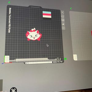 May include: A computer screen displays a 3D printing project. The main focus is a cartoon cat face with a pink bow. The text "Bambu Textured PEI Plate" is visible. Additional 3D printed objects are also shown, including a red hexagon and a small rectangle.