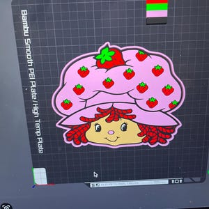 Może przedstawiać: Różowy projekt postaci Strawberry Shortcake z rudymi włosami i pasującym kapeluszem ozdobionym czerwonymi truskawkami. Obraz znajduje się na czarnej powierzchni z tekstem "Bambu Smooth PEI Plate/High Temp Plate".