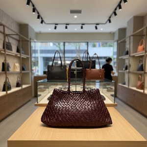 May include: A white ceramic mug with a black handle and the text "But First, Coffee" in a black, handwritten-style font. The mug is on a white surface.