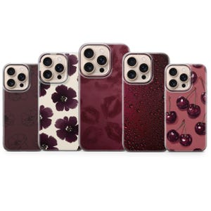 Może przedstawiać: Kolekcja etui na telefony z różnymi wzorami. Etui mają wzory takie jak ciemnofioletowe kwiaty, wiśnie, krople wody i odciski szminki. Etui są w odcieniach bordowego, kremowego i ciemnofioletowego.