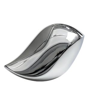 May include: A polished, silver-colored decorative bowl with a flowing, organic shape. The bowl has a smooth, reflective surface that creates a mirror-like effect, reflecting the surrounding environment. The design is modern and minimalist, suitable for home decor.