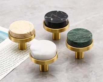 May include: Four cabinet knobs with round marble tops in beige, black, white, and green, set on brass bases. The knobs are designed for furniture and home decor, offering a stylish upgrade.