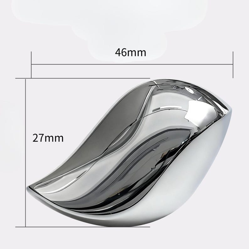 May include: A polished, chrome-finished decorative bowl. The bowl is leaf-shaped, measuring 46mm long and 27mm wide. The reflective surface creates a play of light and shadow, highlighting its smooth curves. The bowl is designed for decorative purposes.