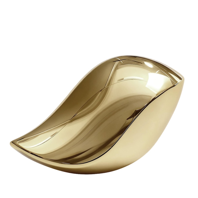 May include: A gold-colored, leaf-shaped decorative bowl. The bowl has a smooth, reflective surface and a curved, organic design. The interior of the bowl is also gold, creating a cohesive and elegant aesthetic. The bowl is likely made of metal.